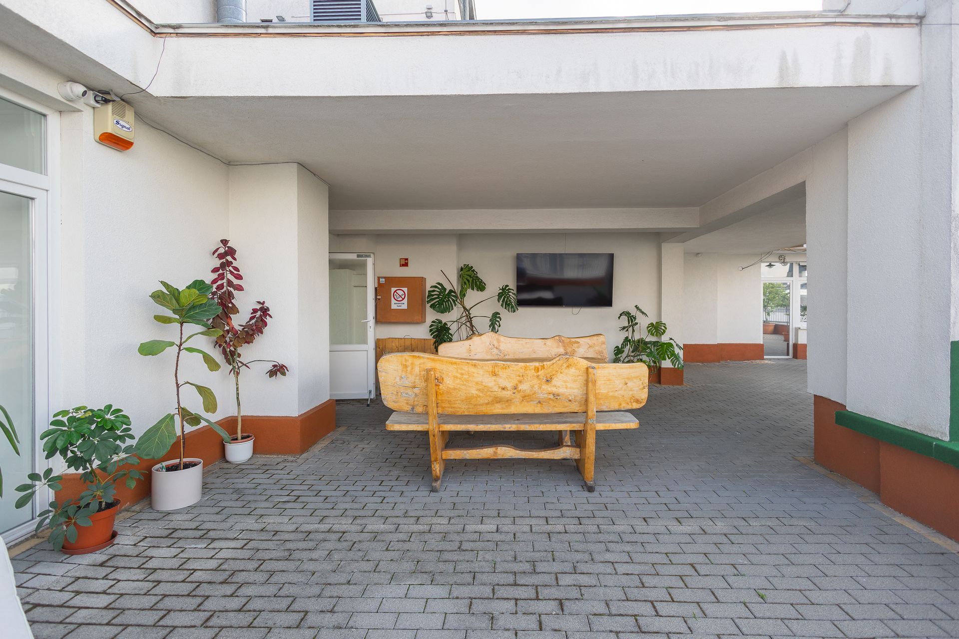 A wooden bench is sitting on a brick pavement in front of a building.
