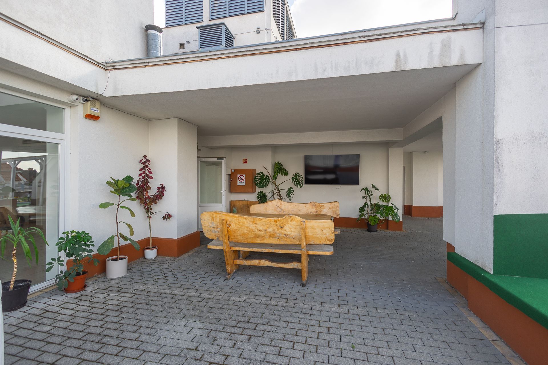 A patio with a wooden bench and a tv on the wall