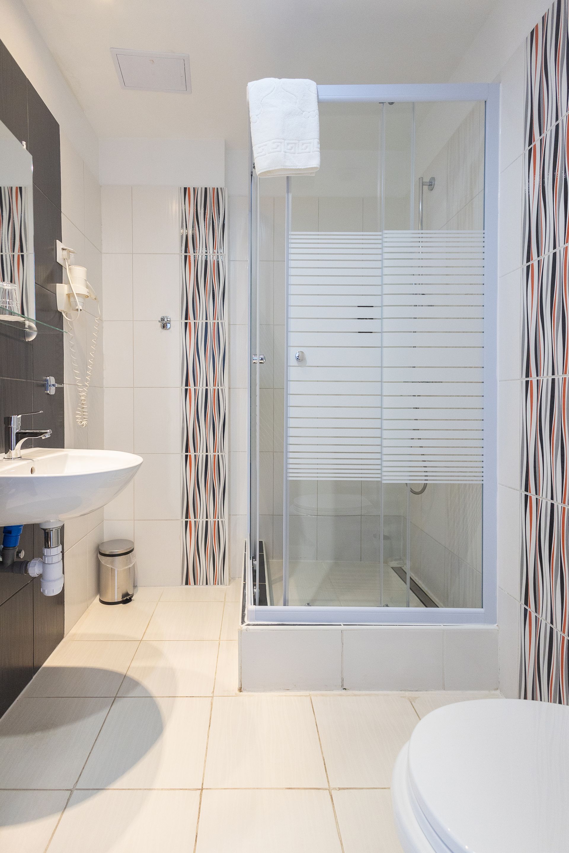 A bathroom with a sink , toilet , shower and mirror.