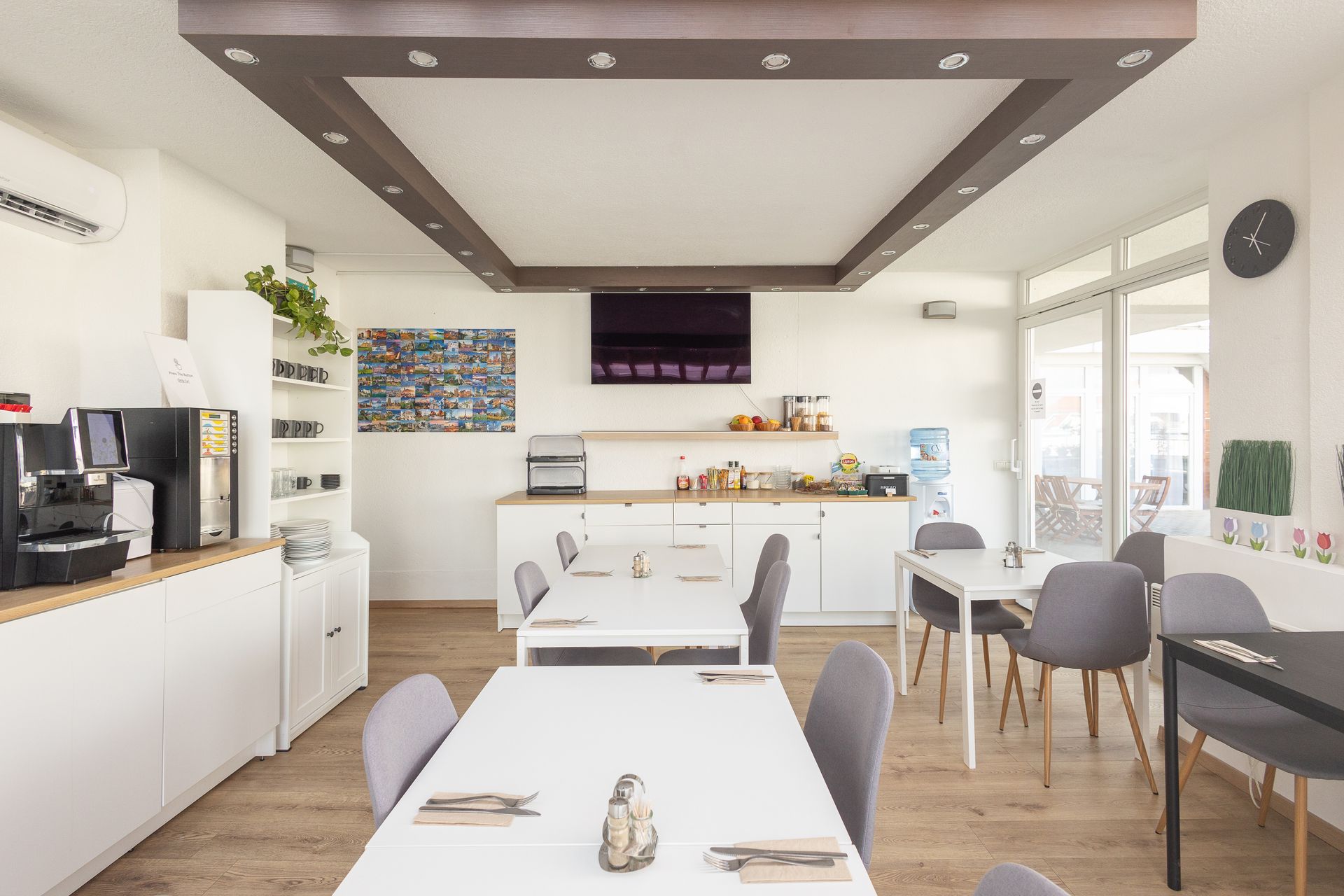 A dining room with tables and chairs and a kitchen.