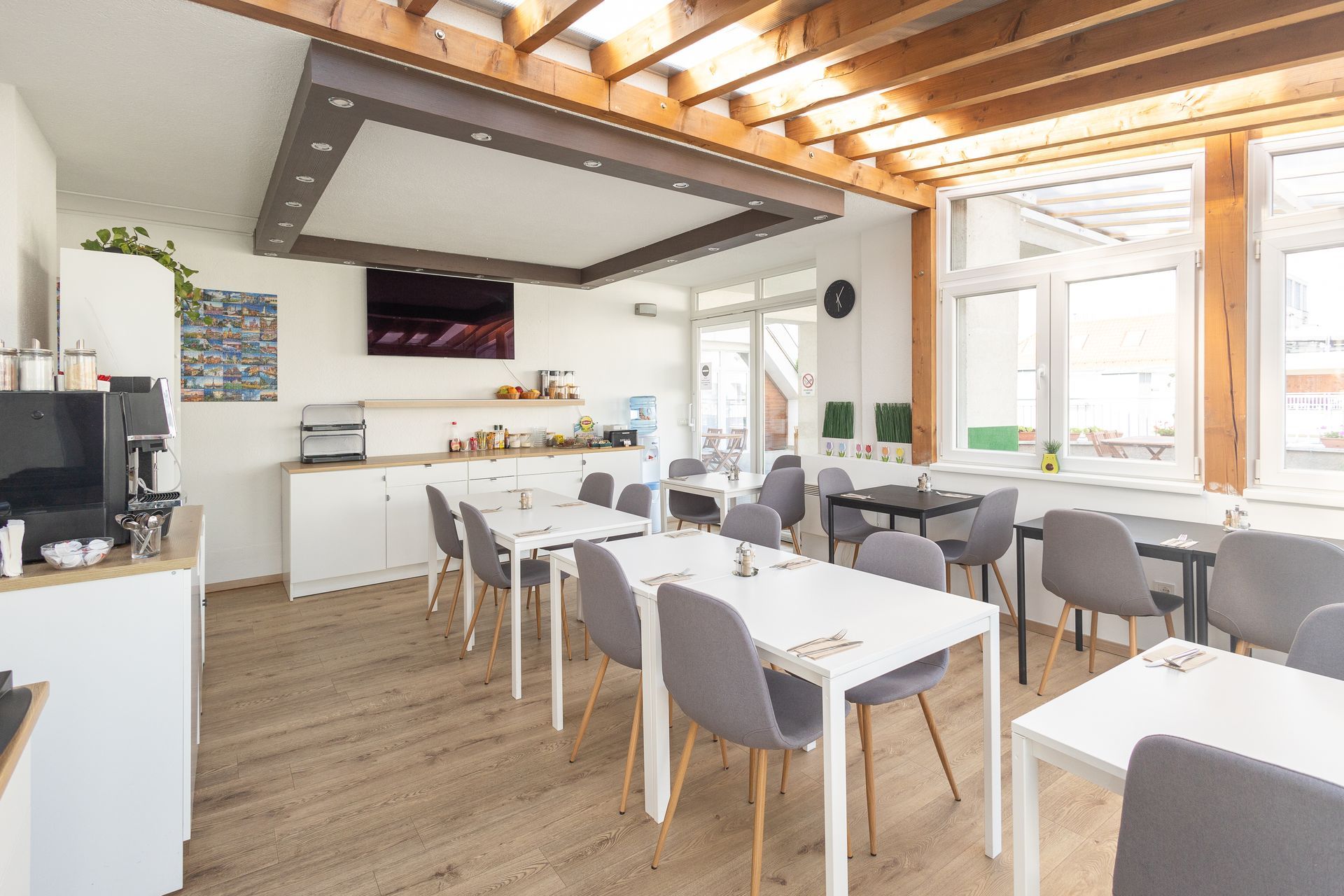 A dining room with tables and chairs and a television on the wall.