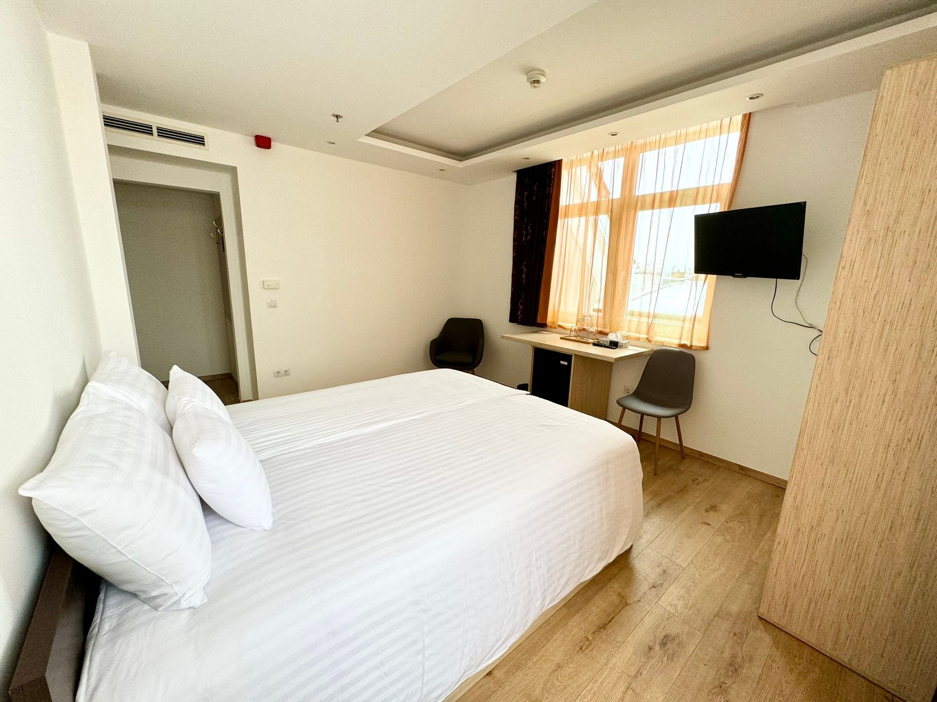 A hotel room with a bed , chair , desk and television.