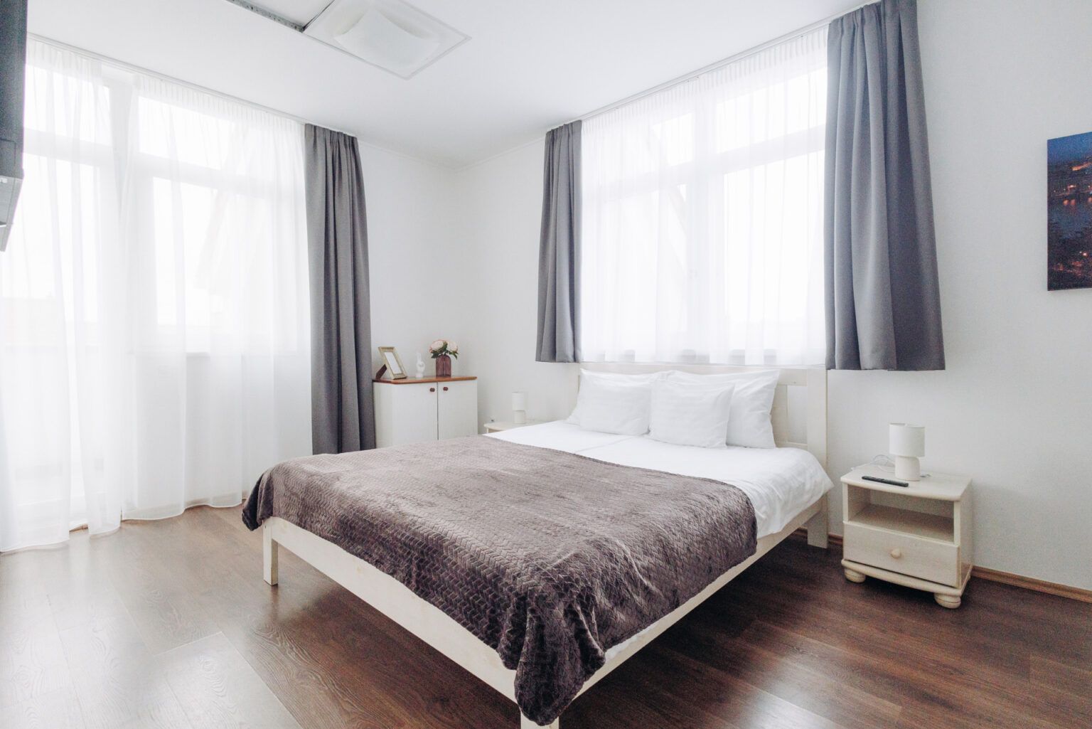 A bedroom with a bed , nightstand , and two windows.