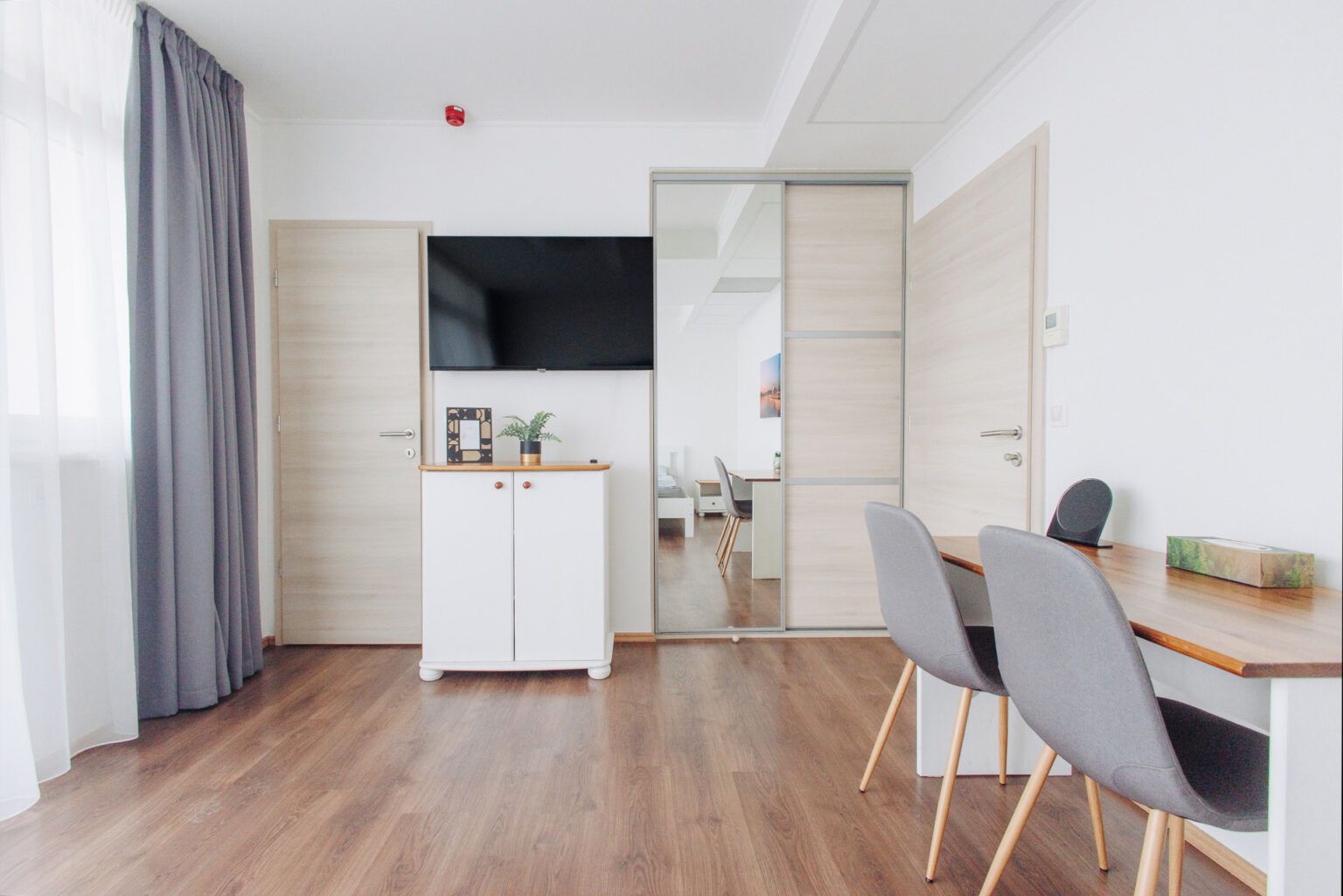 A living room with a table and chairs and a flat screen tv.