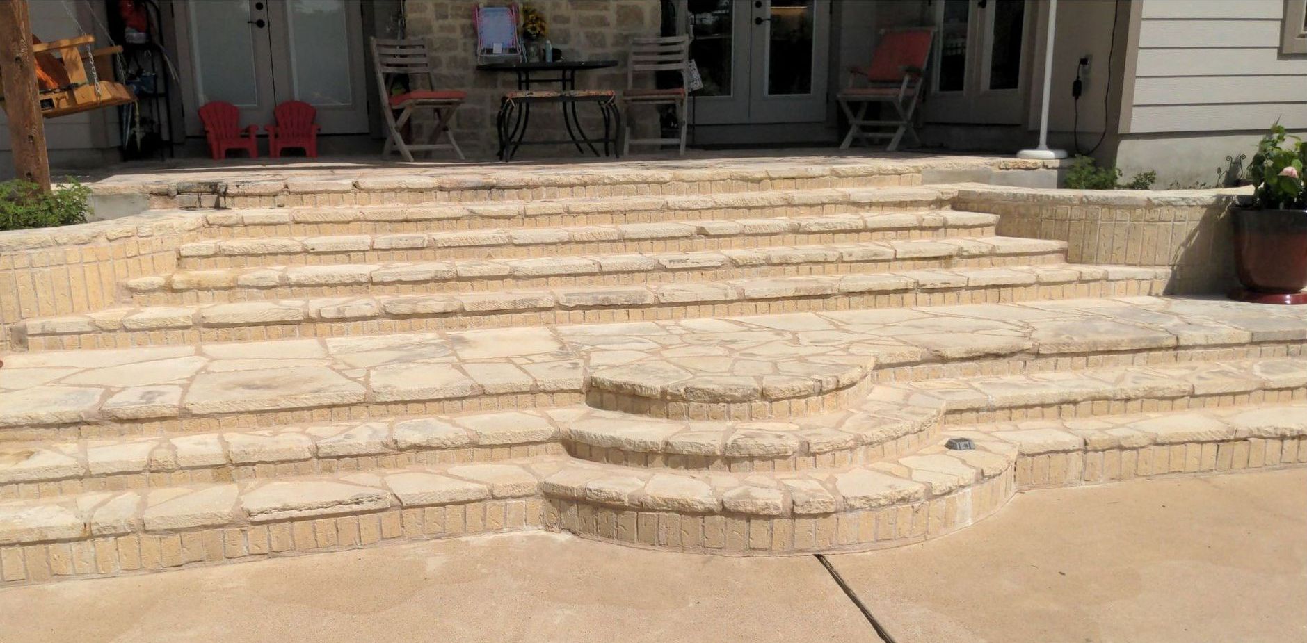 A concrete patio with stairs leading up to a house.