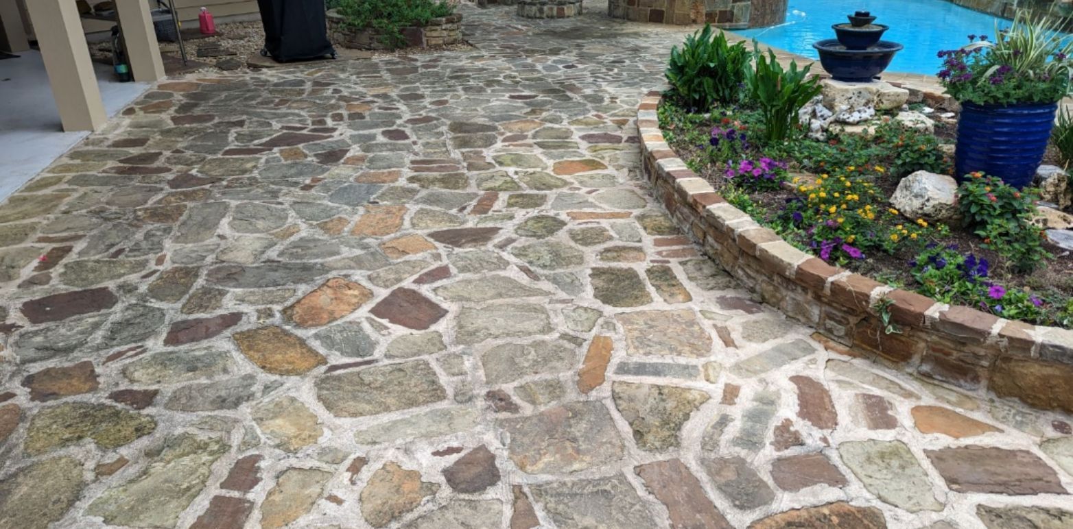 A stone walkway leading to a pool next to a garden.