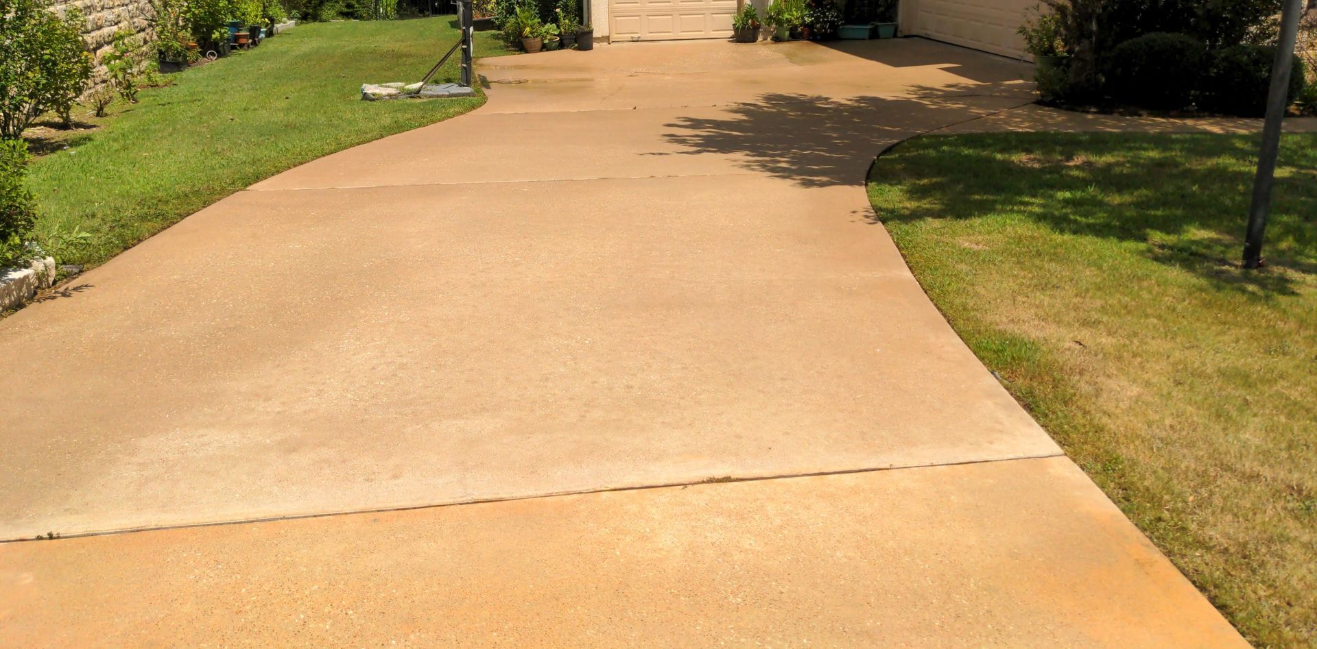 A concrete driveway leading to a house with grass on the side.