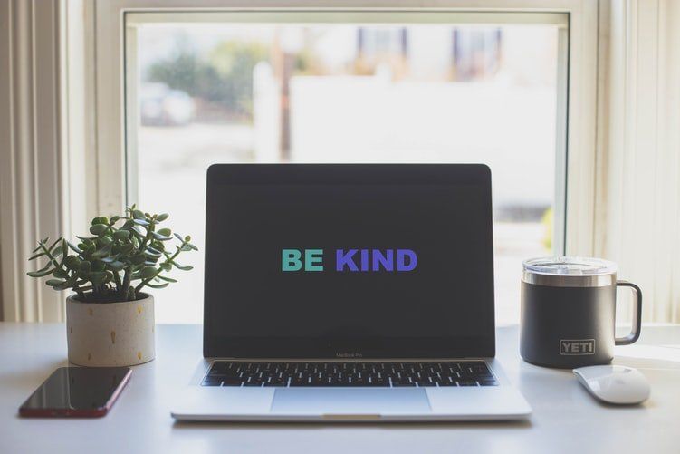 A laptop computer is open to a screen that says `` be kind ''.