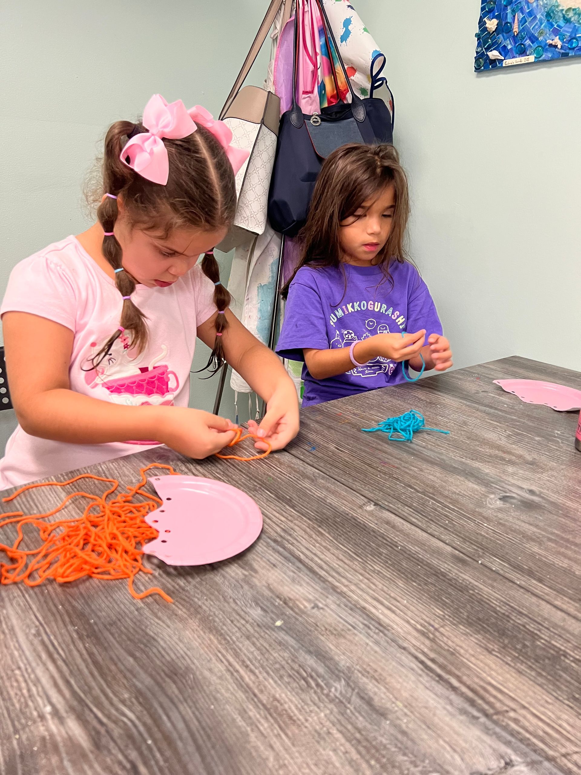 Two little girls are sitting at a table making crafts.