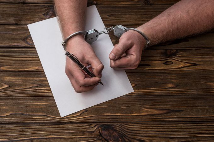 A person in handcuffs signing a document