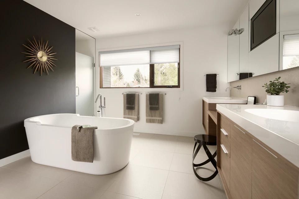 A bathroom with a bathtub , sink , mirror and window.