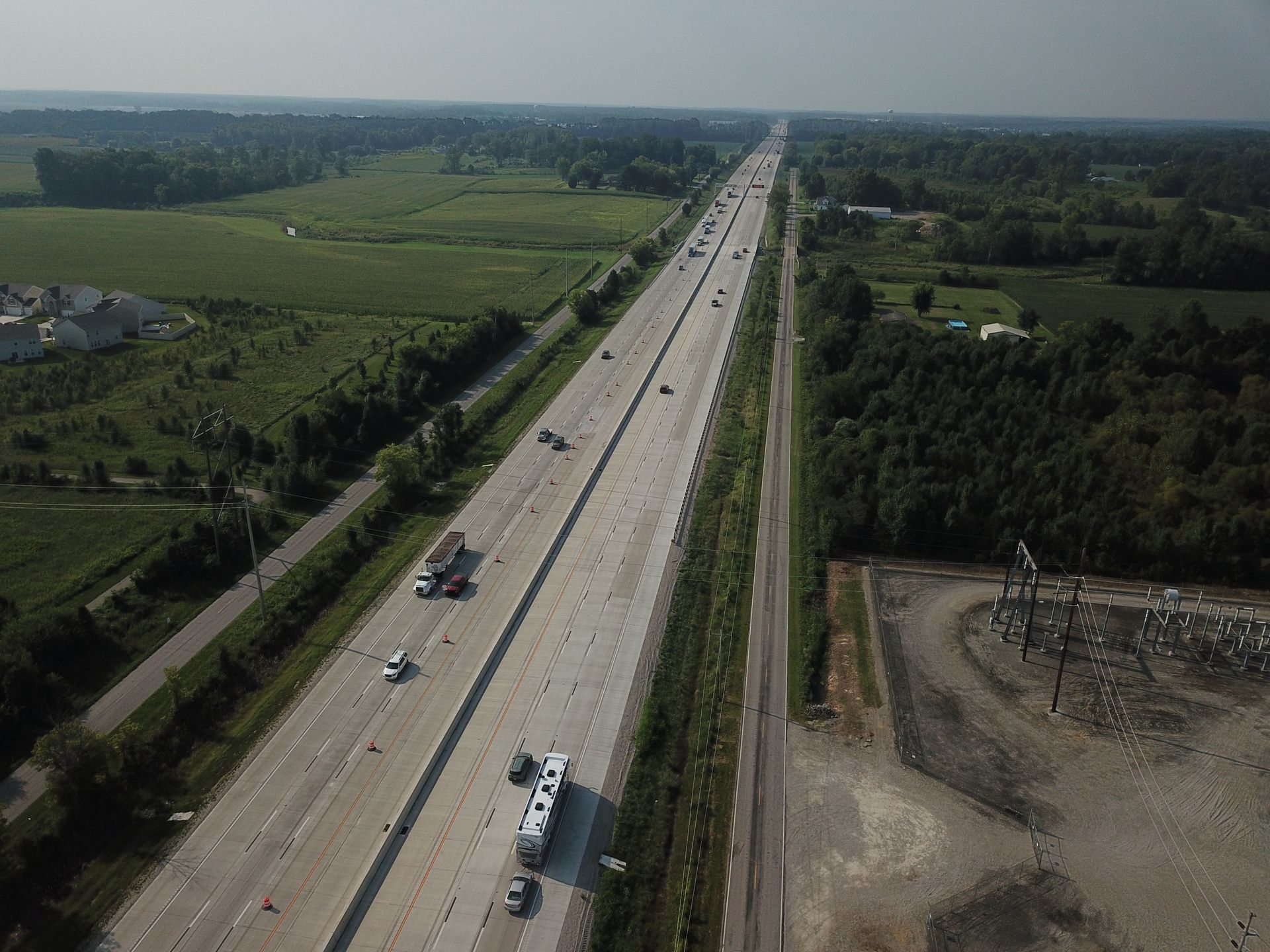 An aerial view of a highway surrounded by trees and fields.