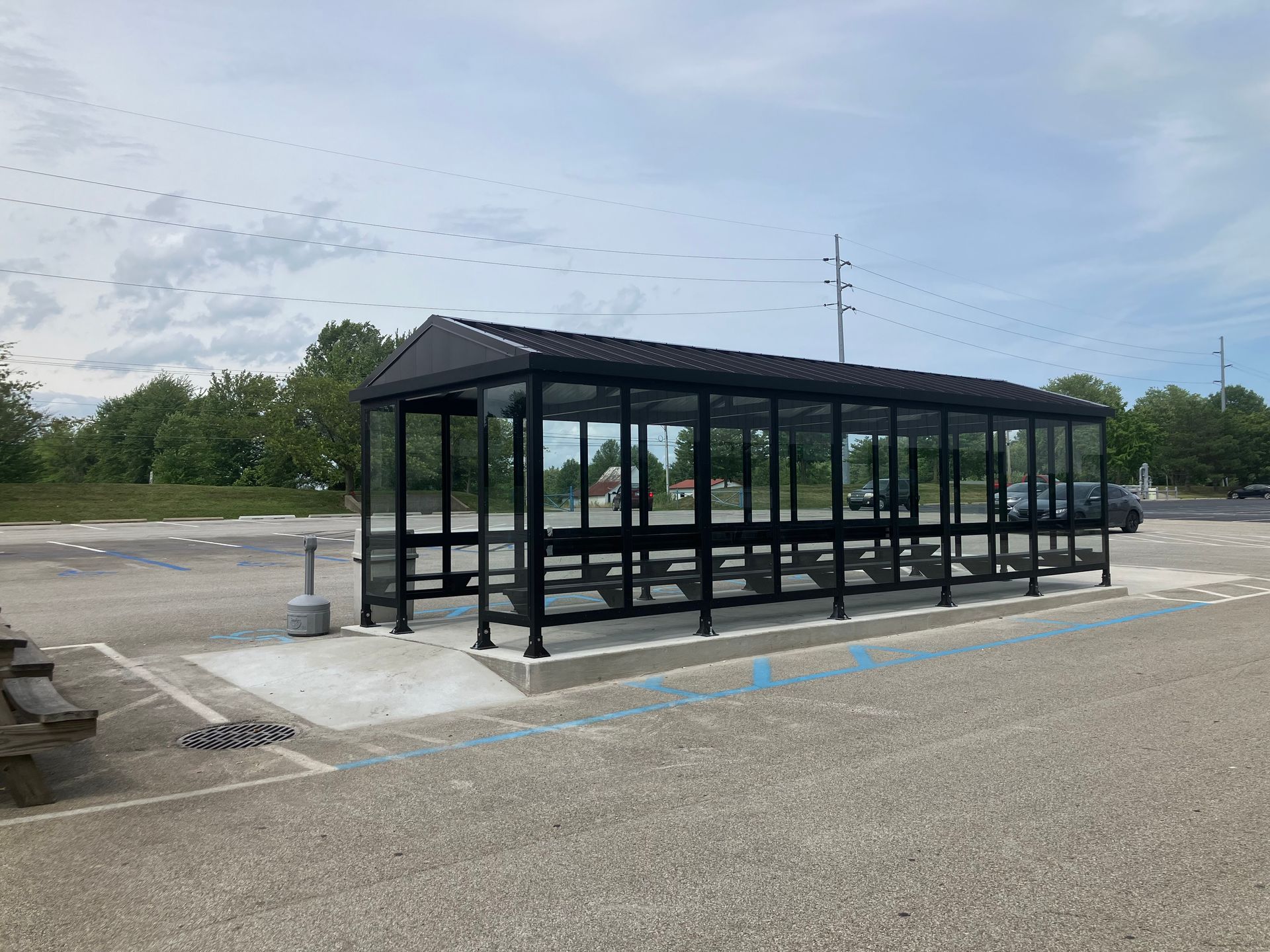 A bus stop shelter with a picnic table in a parking lot.