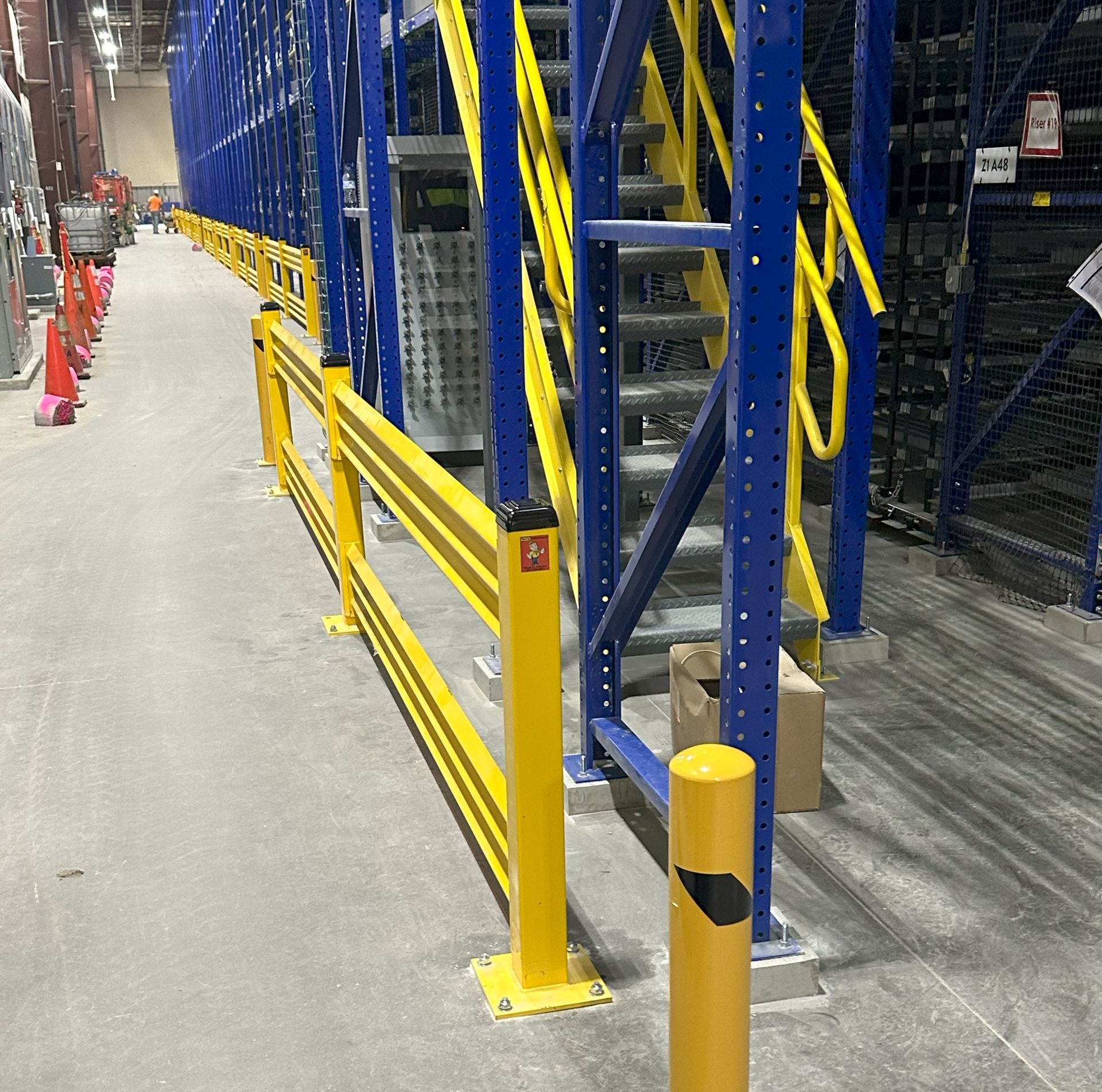 A warehouse with blue shelves and yellow stairs