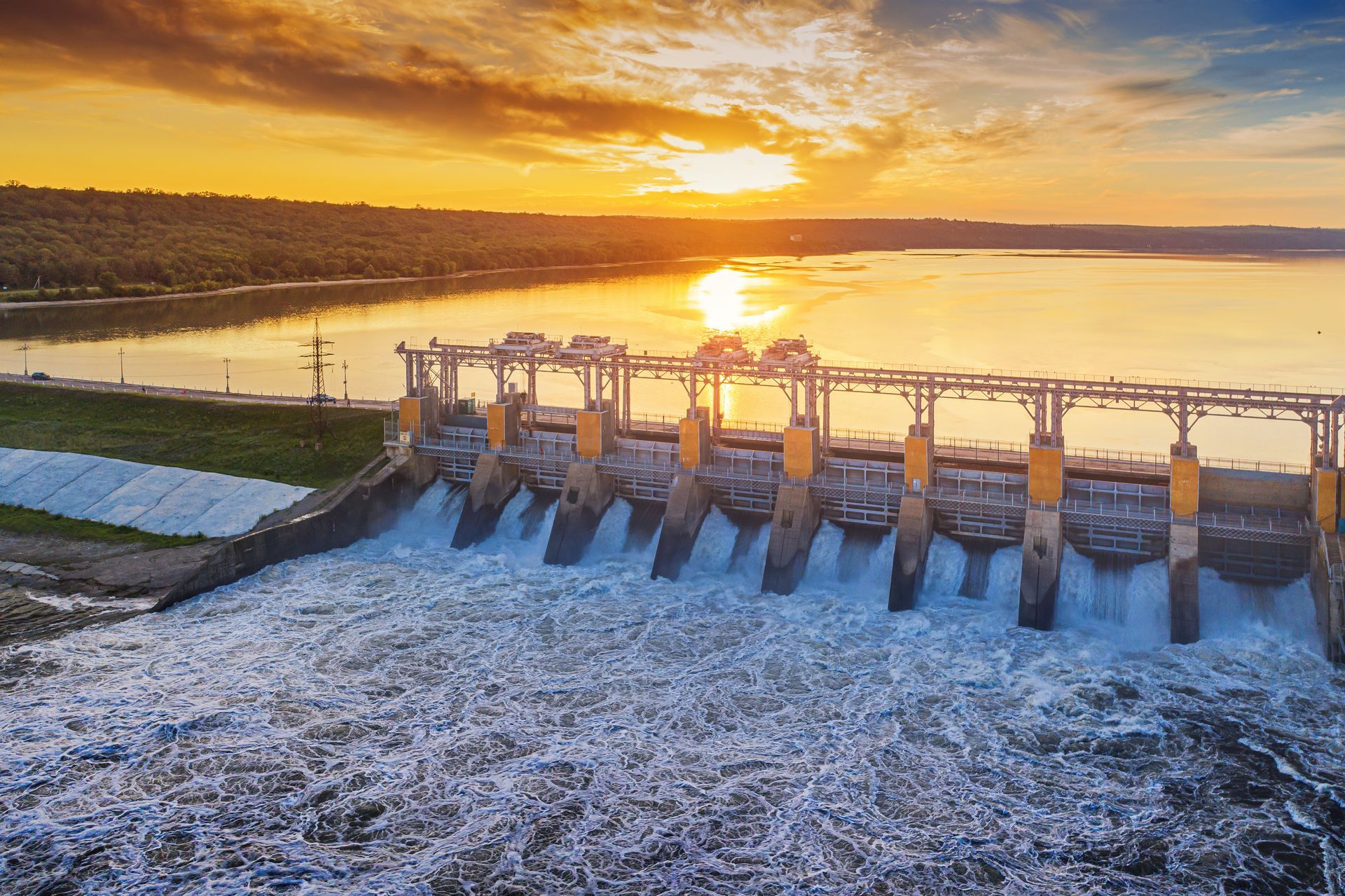 an aerial view of a dam at sunset with water coming out of it .
