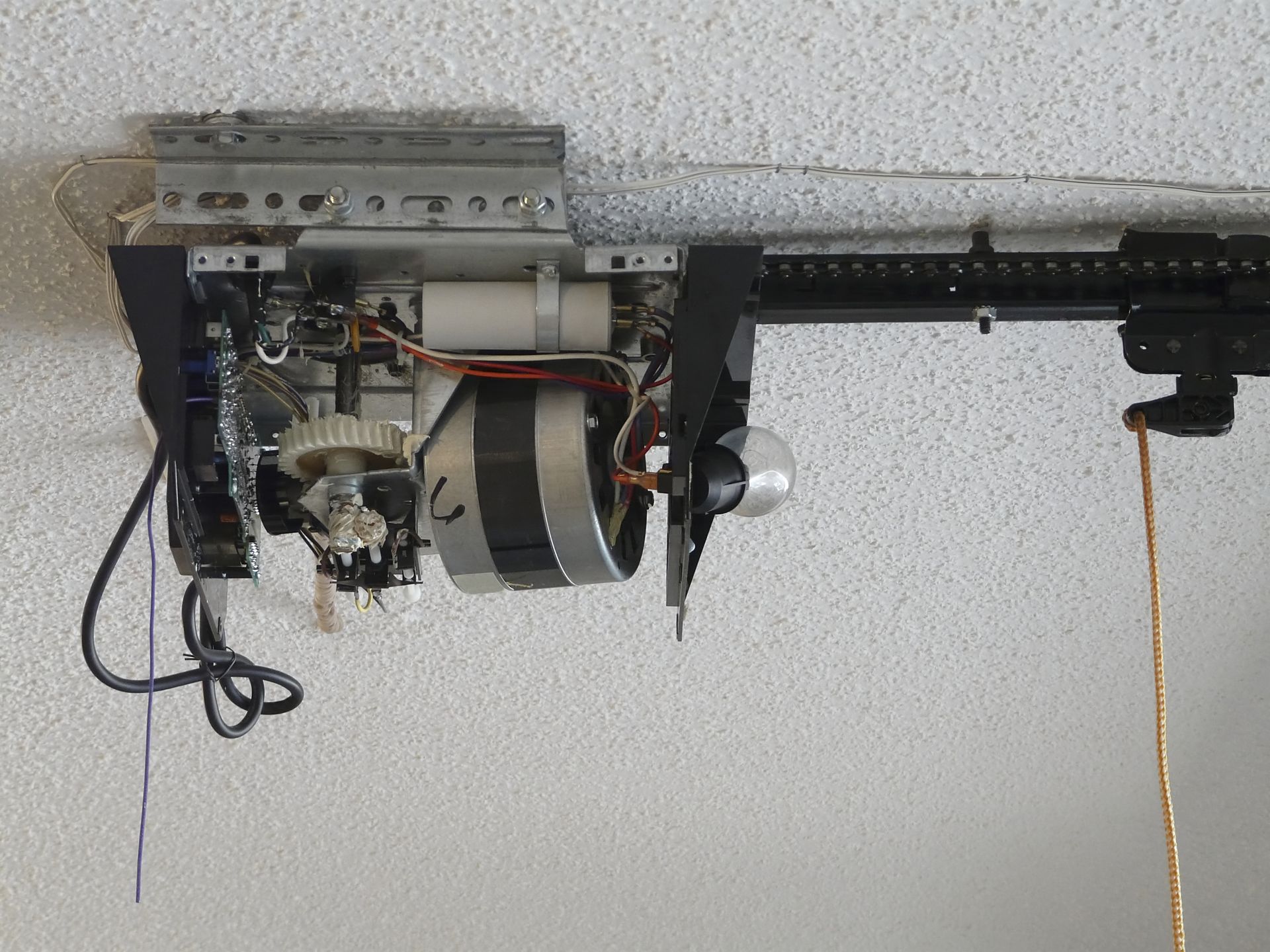 Garage door opener mechanism mounted on a white ceiling.