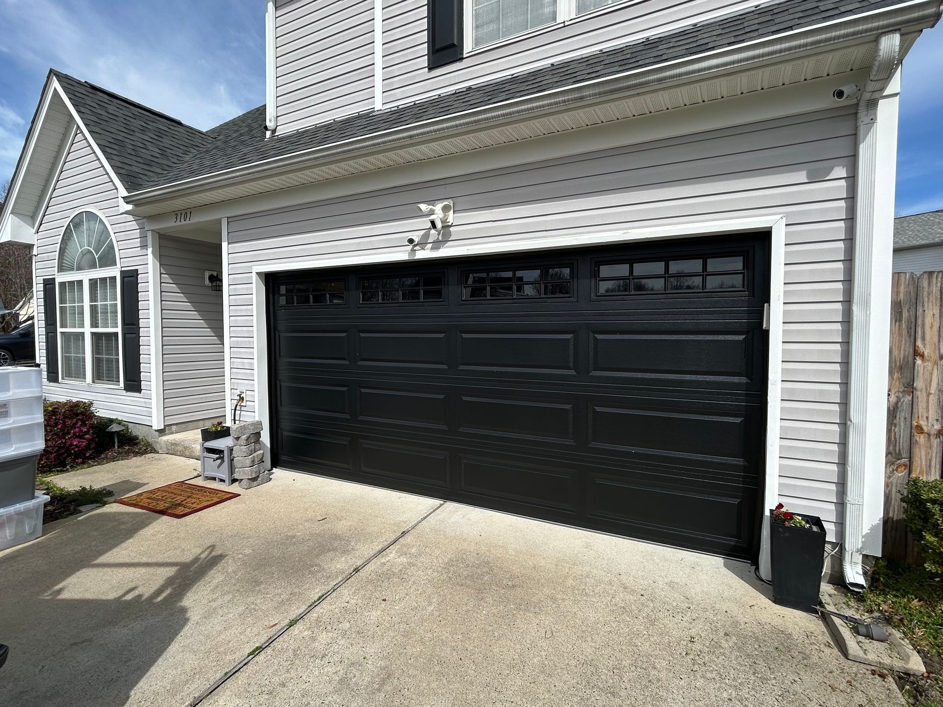 Black garage door on a two-story gray house. 