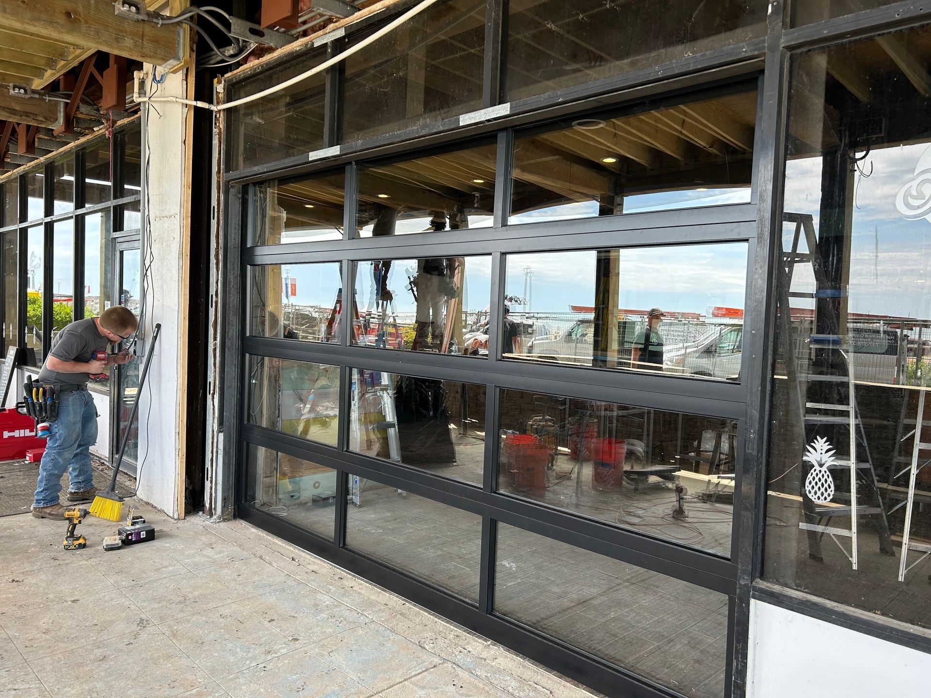 A person installs a large glass door in a building under construction.