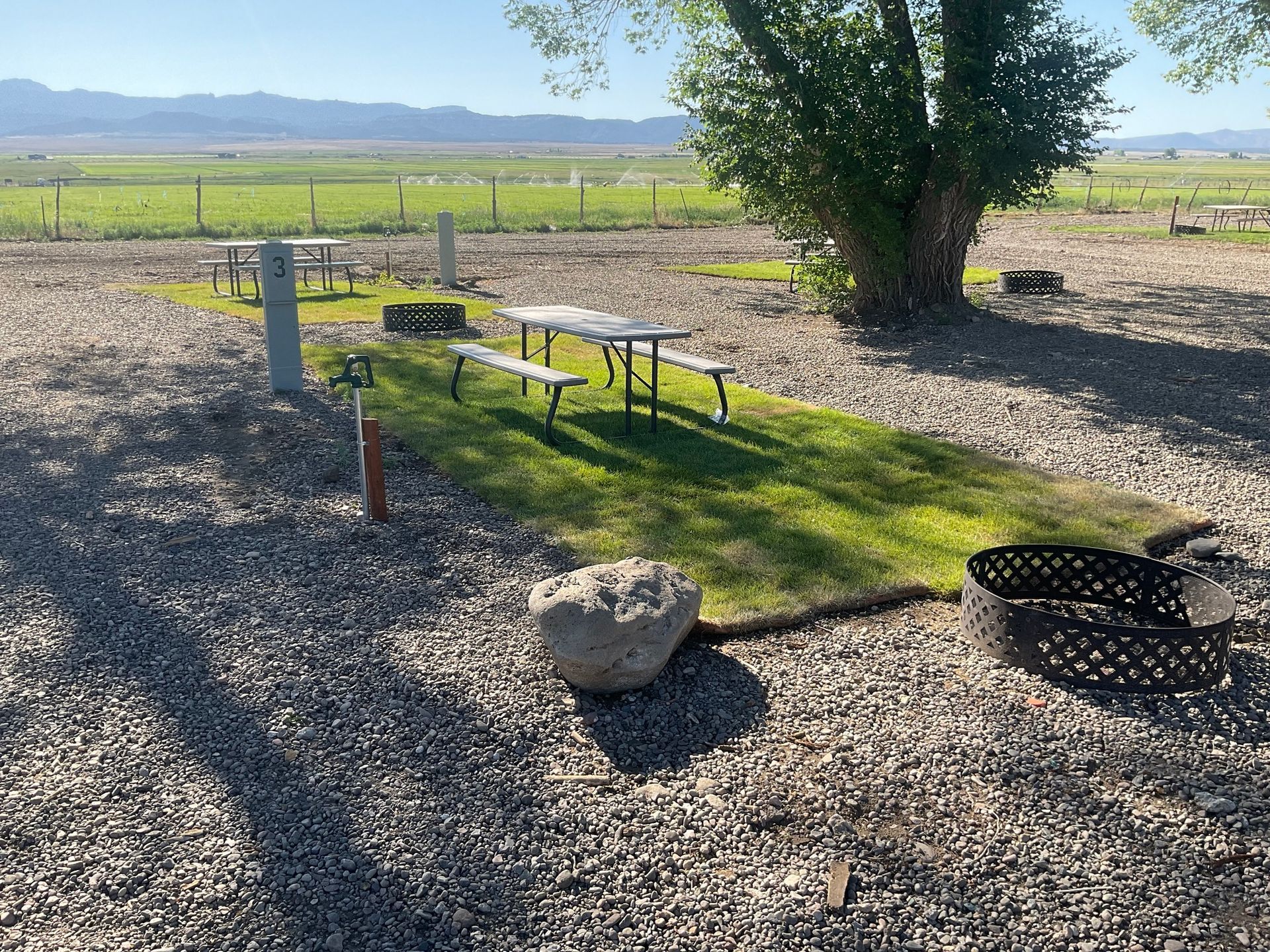 A picnic table and benches in a gravel area with a fire pit.