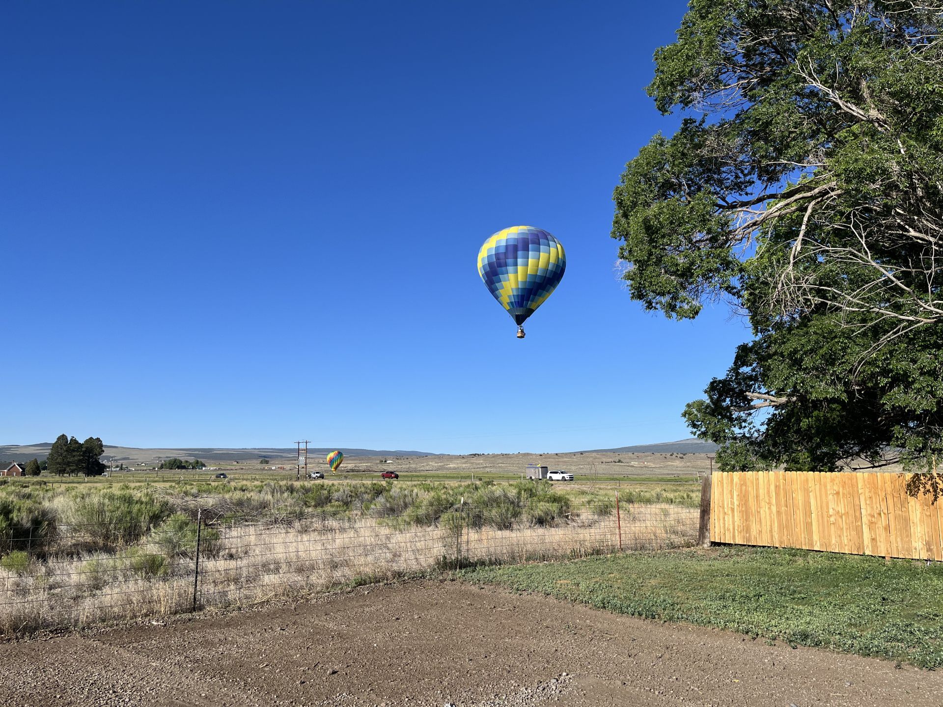 A hot air balloon is flying over a dirt road