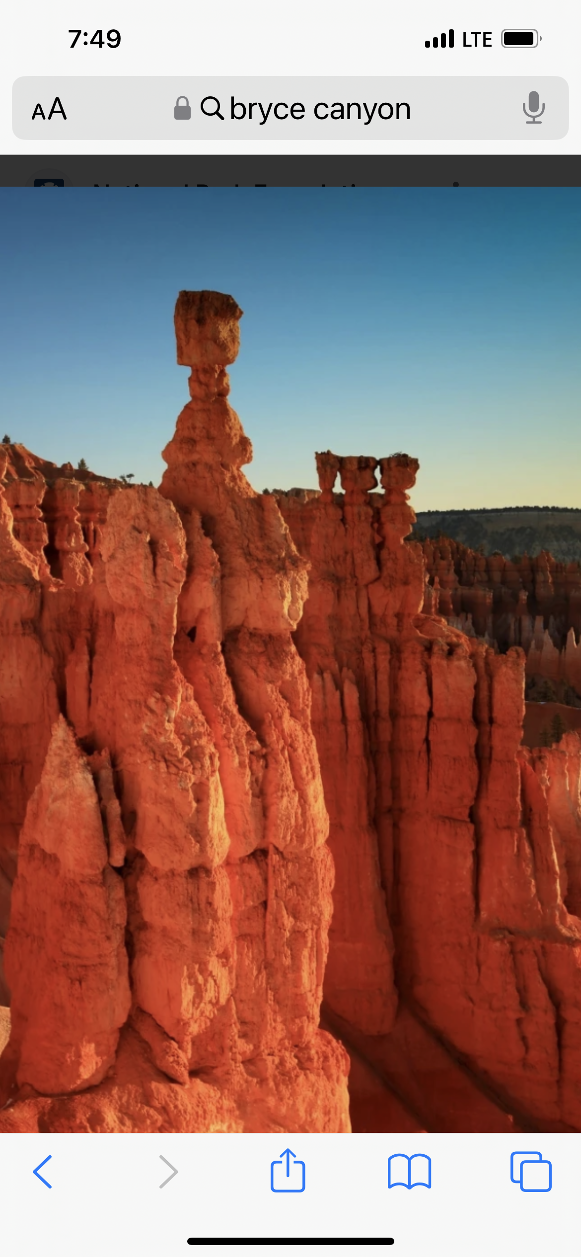A phone screen shows a picture of a canyon.