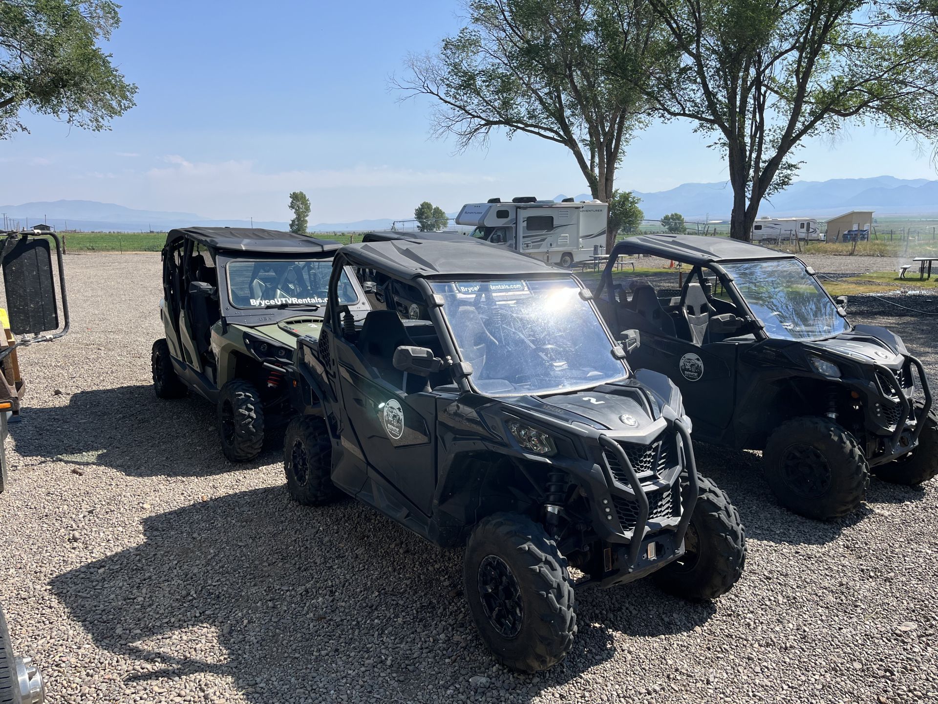 Two atvs are parked next to each other in a gravel lot.
