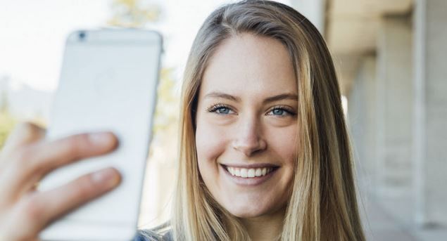 A woman is taking a selfie with her cell phone.