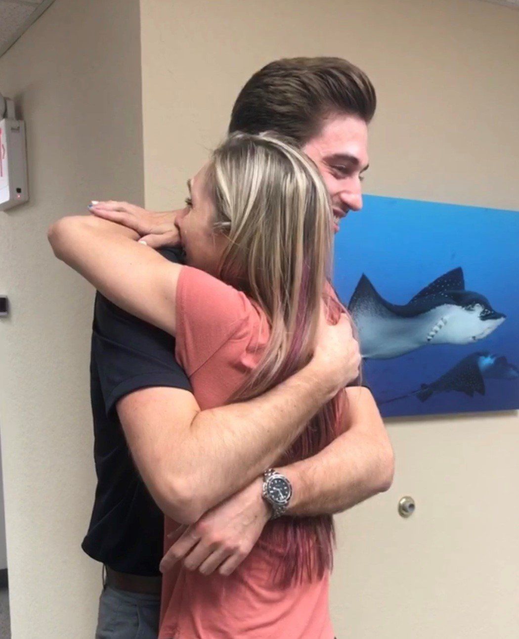 A man and woman hugging in front of a painting of a dolphin