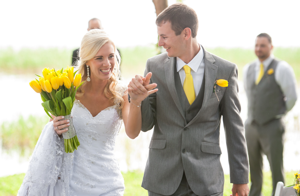 A bride and groom are walking down the aisle holding hands