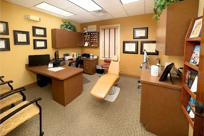 Dental office room with dental chair, desk, cabinets, and diplomas.