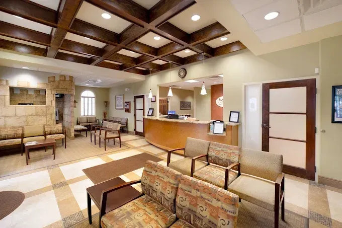 Waiting room with chairs, a reception desk, stone accents, and wood ceiling beams.