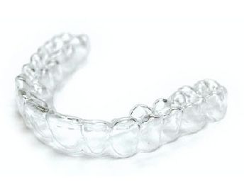 A clear mouth guard is sitting on a white surface.