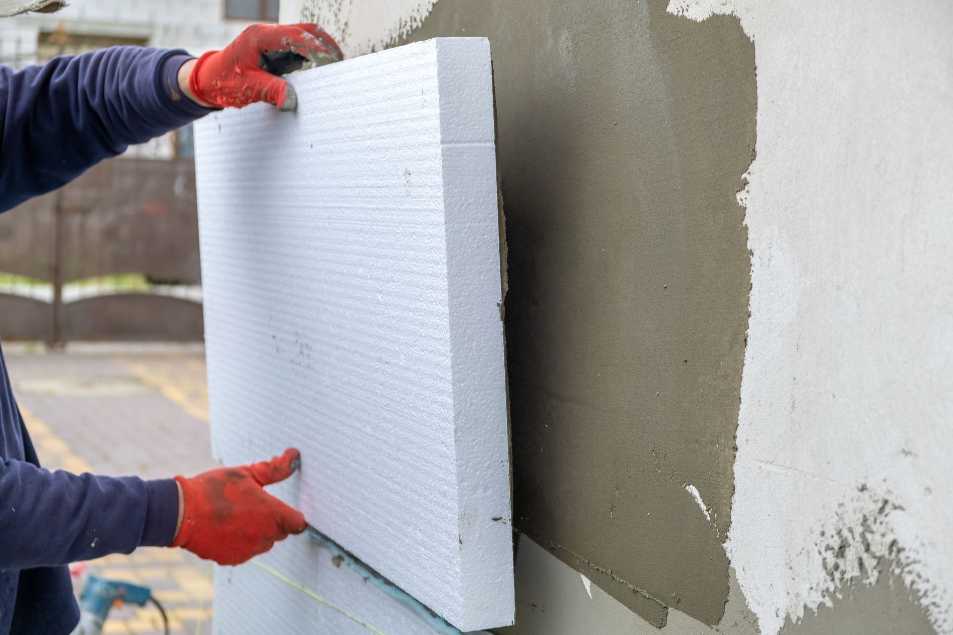 A builder worker installing insulation panels on a wall. A builder worker installing insulation panels on a wall.