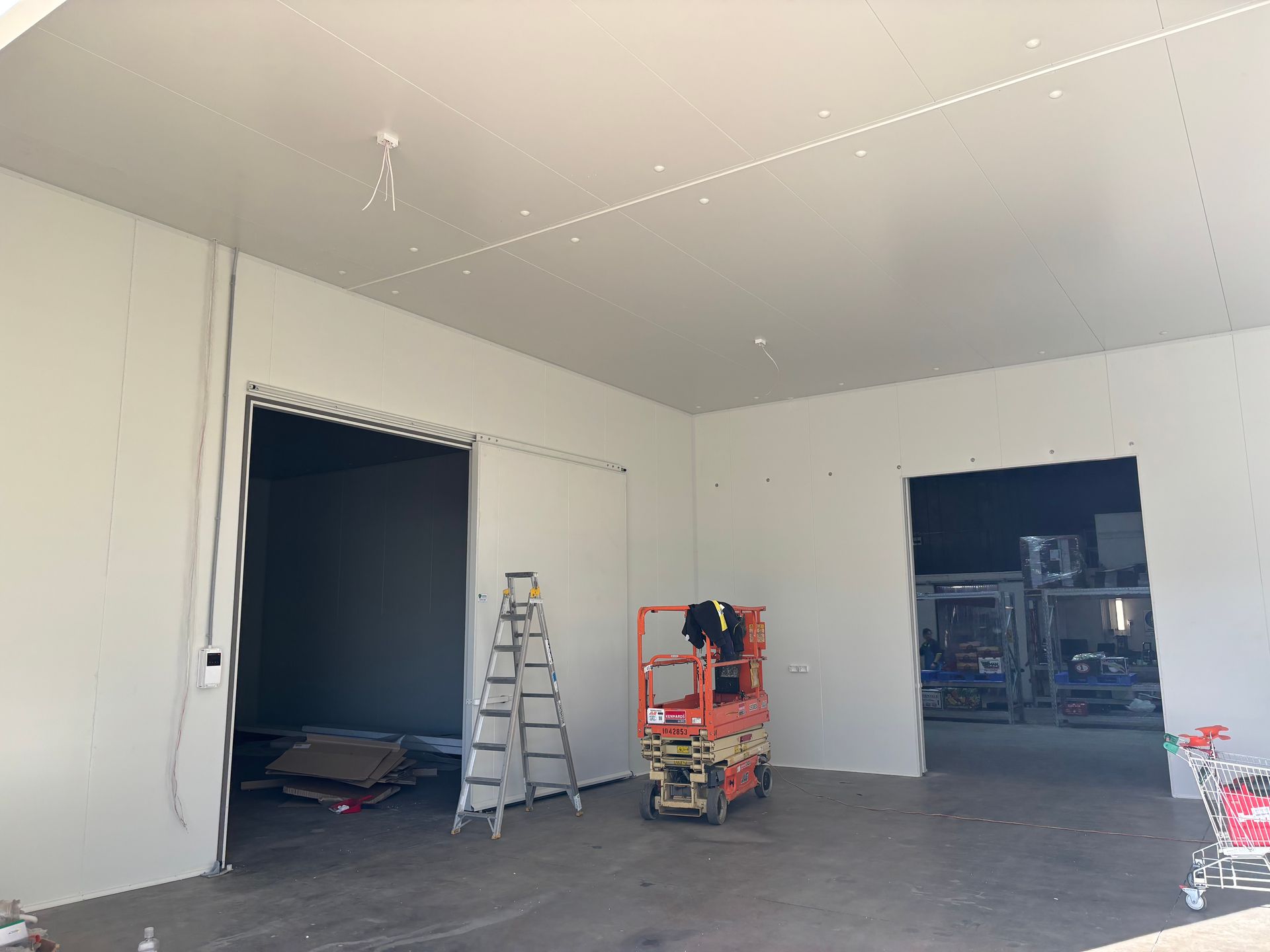 Mini-scissors lift being used during cool room construction in an unfinished space. Mini-scissors lift being used during cool room construction in an unfinished space.