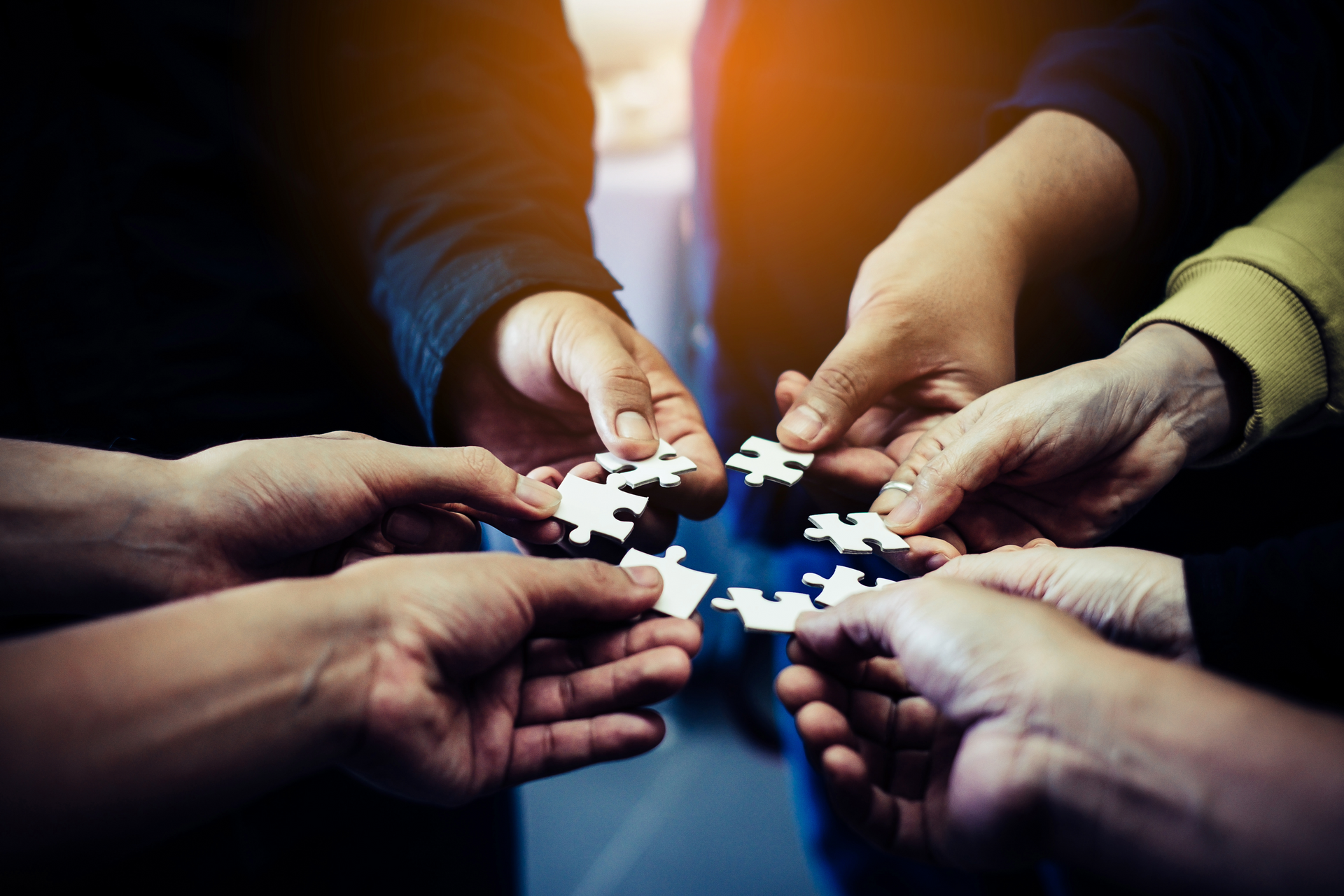 A group of people are putting puzzle pieces together in a circle.