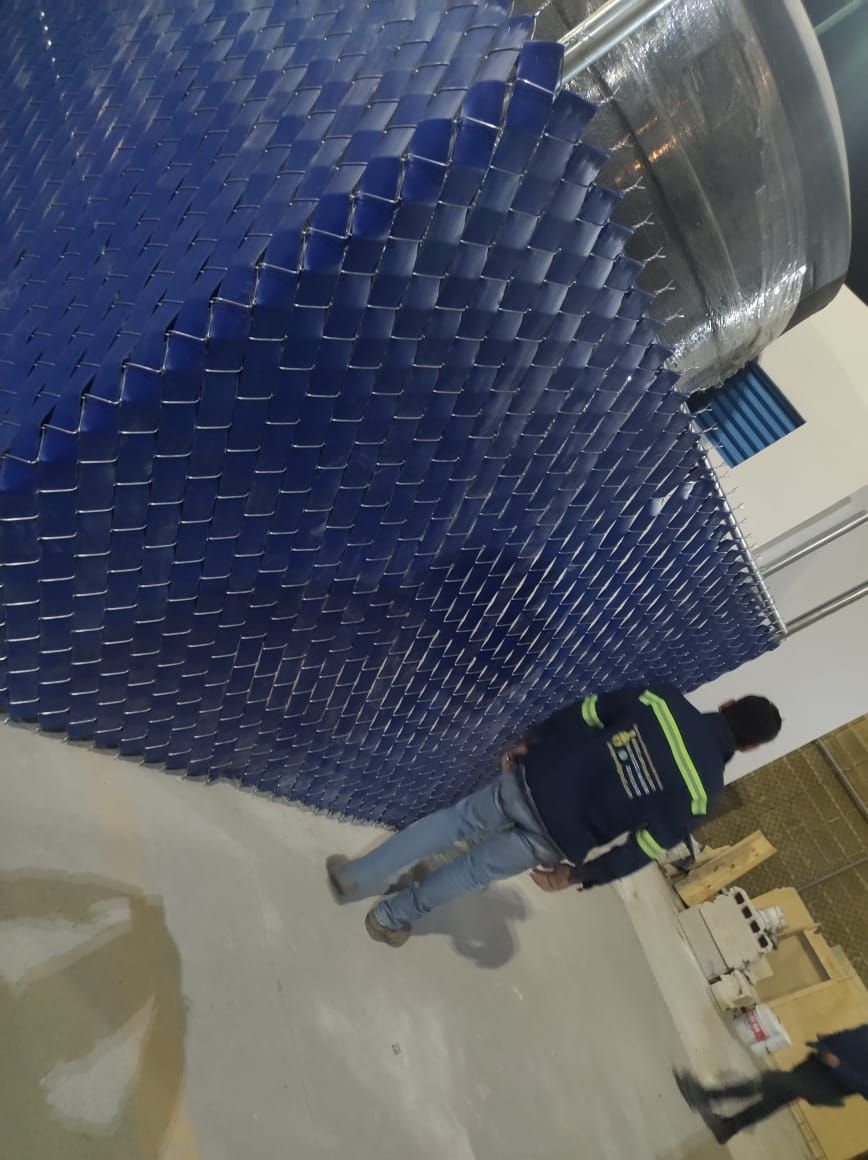 Estructura azul similar a un panal en un techo con un trabajador parado cerca.