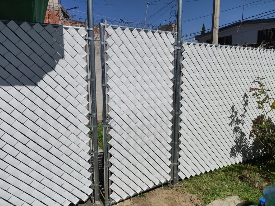 Valla de privacidad blanca con estructura de eslabones de cadena y puerta.