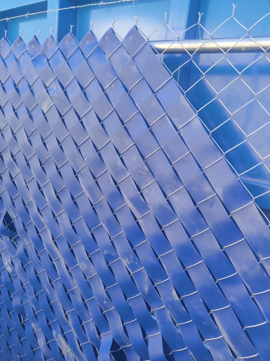 Tiras de plástico azul tejidas a través de una cerca de alambre, creando una pantalla de privacidad.