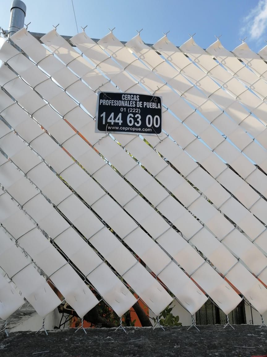 Valla de listones diagonales de color blanco con un cartel negro que muestra los números 