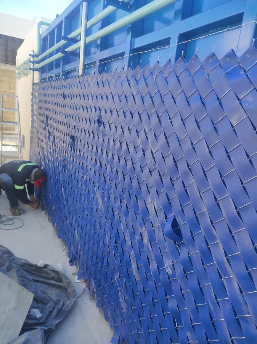 Trabajador suelda panel de torre de enfriamiento de plástico azul.