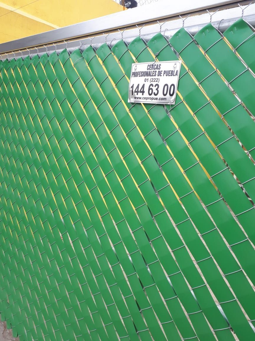 Valla de alambre verde con listones verdes. Letrero con el número de teléfono 144 63 00.