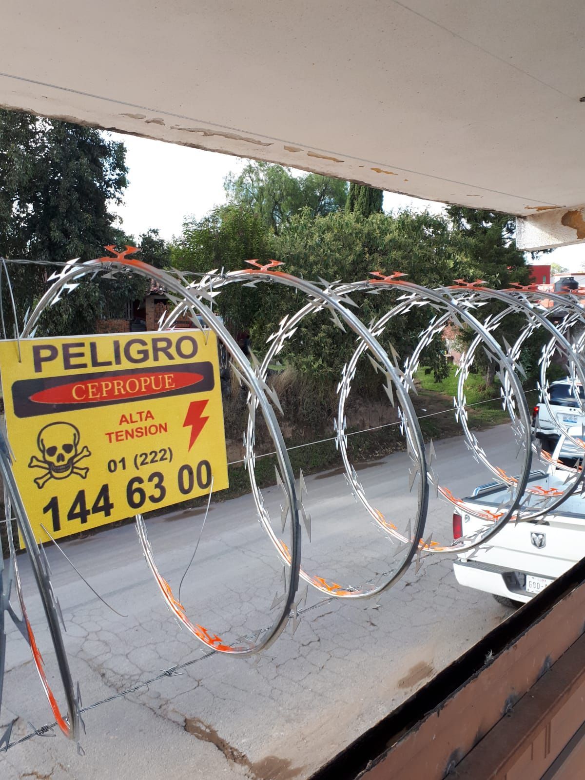 Señal de advertencia con alambre de púas de alto voltaje. Símbolo de calavera. Señal amarilla con alambre gris y plateado.