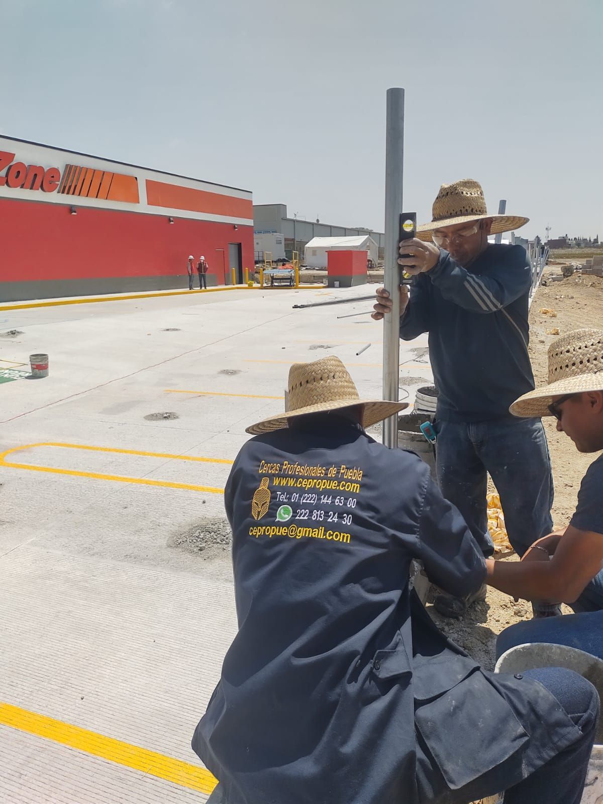 Tres obreros instalando un poste con niveles cerca de una tienda. Atardecer soleado.