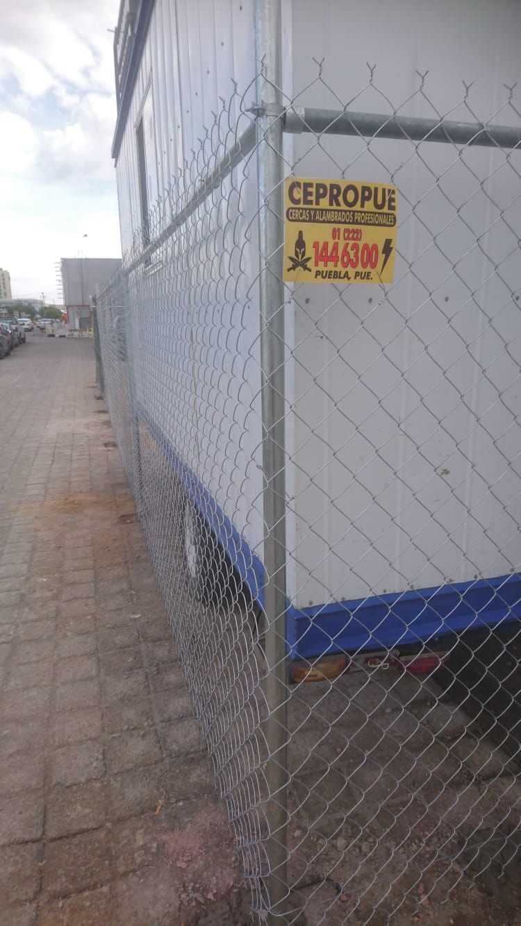 Una valla metálica rodea un edificio blanco. Letrero amarillo de CEPROPUE.