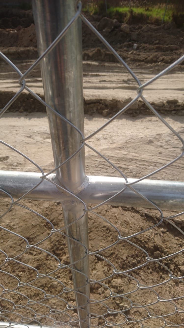 Primer plano de un poste de una cerca de alambre. Un poste de metal plateado y una barra horizontal están conectados a la cerca.