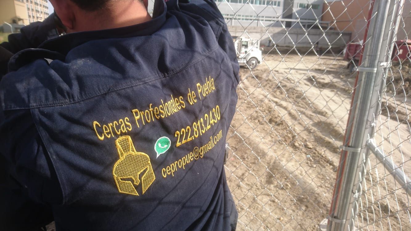 Persona instalando cerca de alambre; camisa de trabajo azul con logo: 