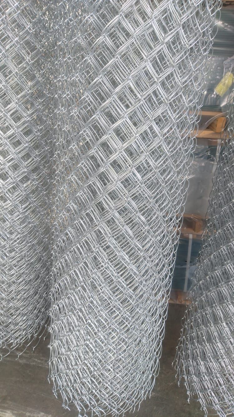 Valla de alambre enrollado, de metal plateado, apilada en interior.