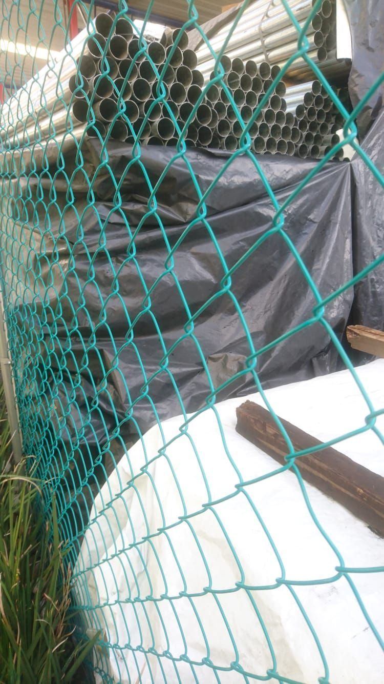 Red verde en primer plano. Detrás, plástico negro y montones de tubos verde oscuro.