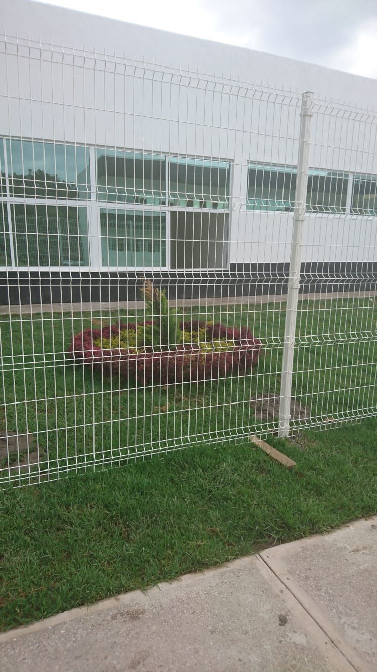 Edificio blanco detrás de una valla decorativa de metal blanco con un pequeño jardín en el frente.