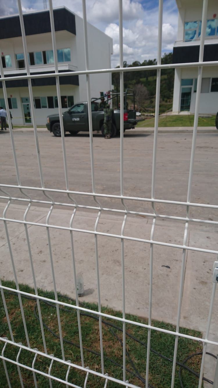 Personal militar y vehículo detrás de una valla cerca de edificios.